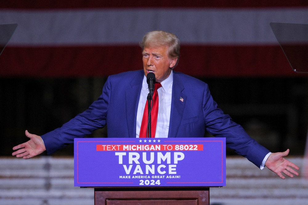 Trump stands at podium, arms opened wide in gesture. 