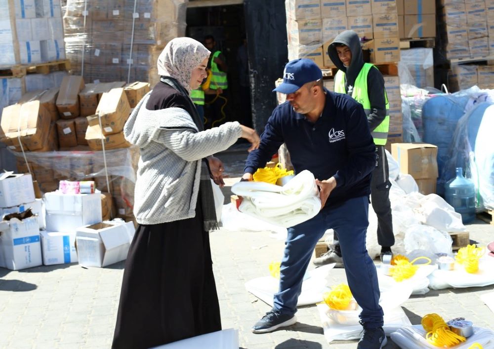 A Catholic Relief Services worker distributes shelter material to a woman in Rafah, in the southern Gaza Strip, March 21. 