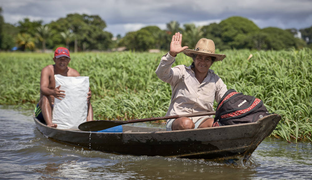 A woman waves while paddling a canoe in Santarem, a city in Brazil's northern Para state, April 11, 2019. At the time, one river in the Archdiocese of Santarem has 54 Catholic communities along its banks and only one priest to serve all these communities. (CNS photo/Paul Jeffrey)