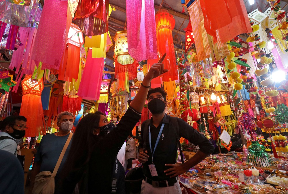 Vibrant stall hung with lanterns, people point and look.