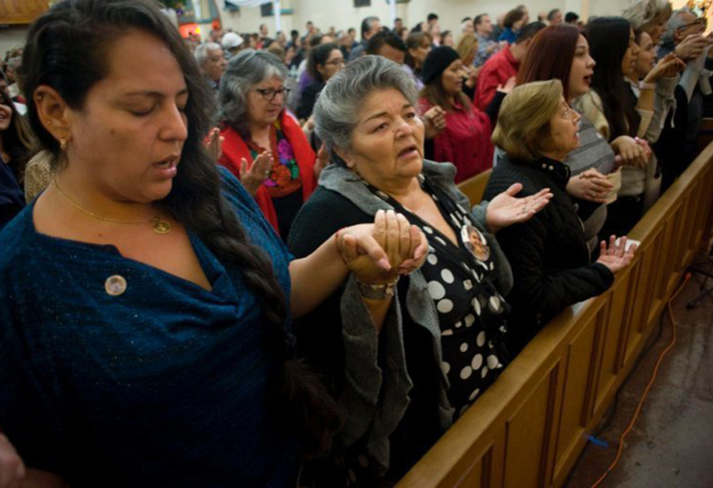 Worshippers recite the Lord's Prayer during a Mass celebrated in honor of the 100th anniversary of Our Lady of Guadalupe Church, Dec. 9, 2017, in San Diego. The church was first founded to serve the recently arrived Mexican population in San Diego, and has become a cornerstone of the local Latino Catholic community. (OSV News/David Maung)