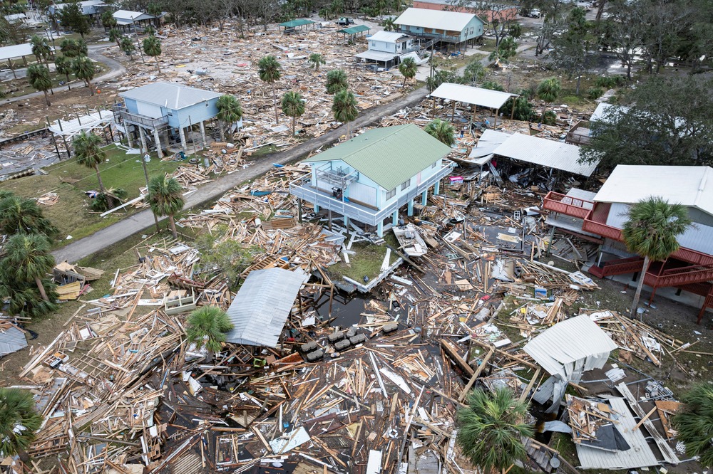 Aerial view of devastated town; ground strewn with wreckage, few buildings remain. 