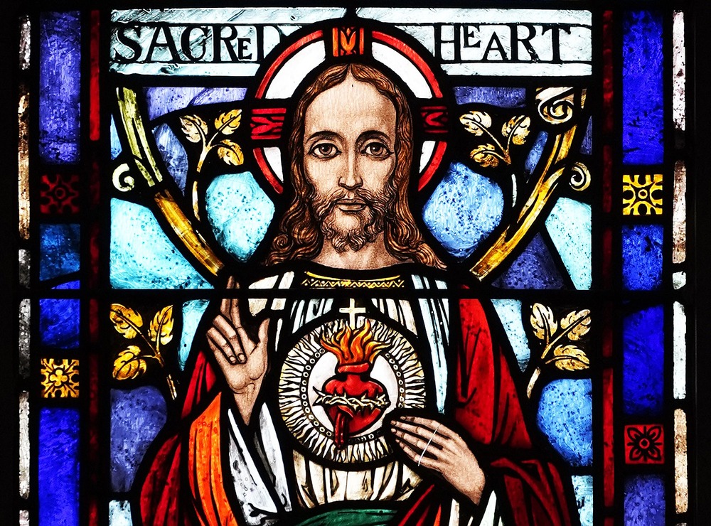 Stained glass image of Jesus bearing his Sacred Heart. 