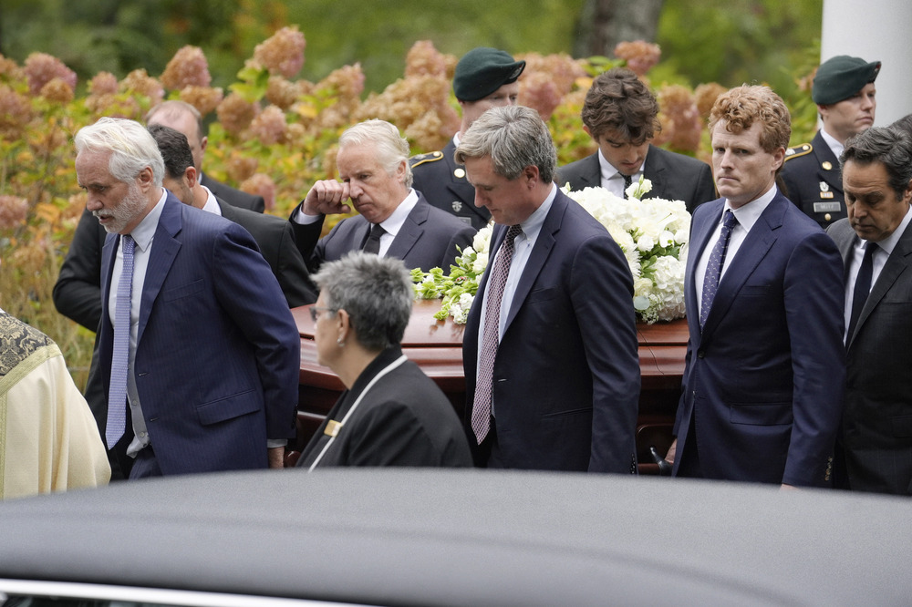 The men walk carrying casket.