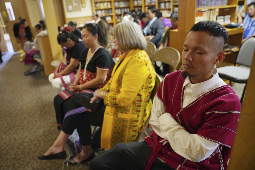 People seated in rows, eyes closed. 