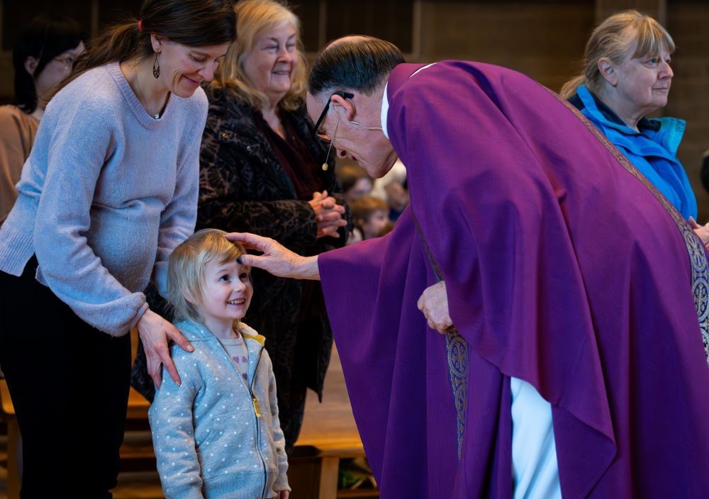 Fr. Bob Kabat distributes ashes to a young child during Ash Wednesday Mass Feb. 14. 