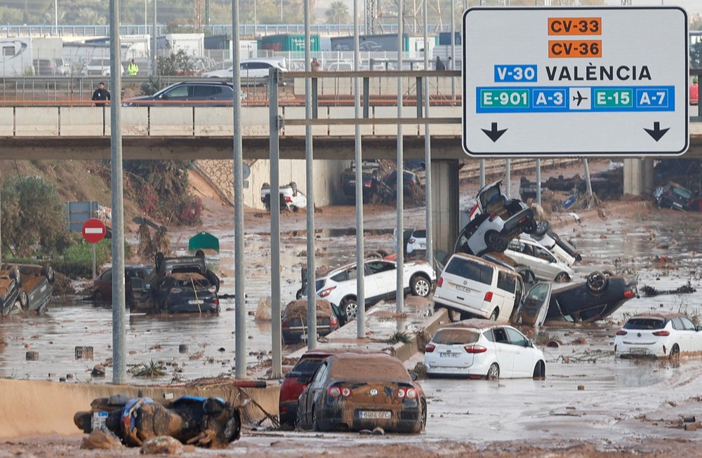 What appears to be an eight-lane highway is covered with mud and abandoned, overturned cars.