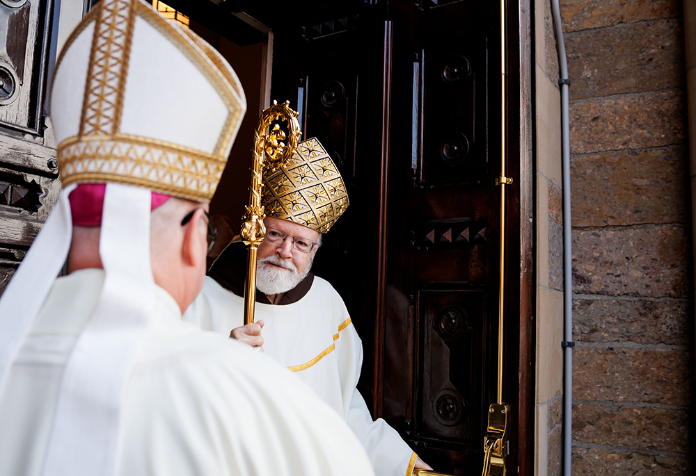 Cardinal Sean O'Malley opens the door of the Cathedral of the Holy Cross to greet Archbishop Richard Henning at the start of the Mass to install Henning as archbishop of Boston, on Oct. 31. (OSV News/The Pilot/Gregory L. Tracy)