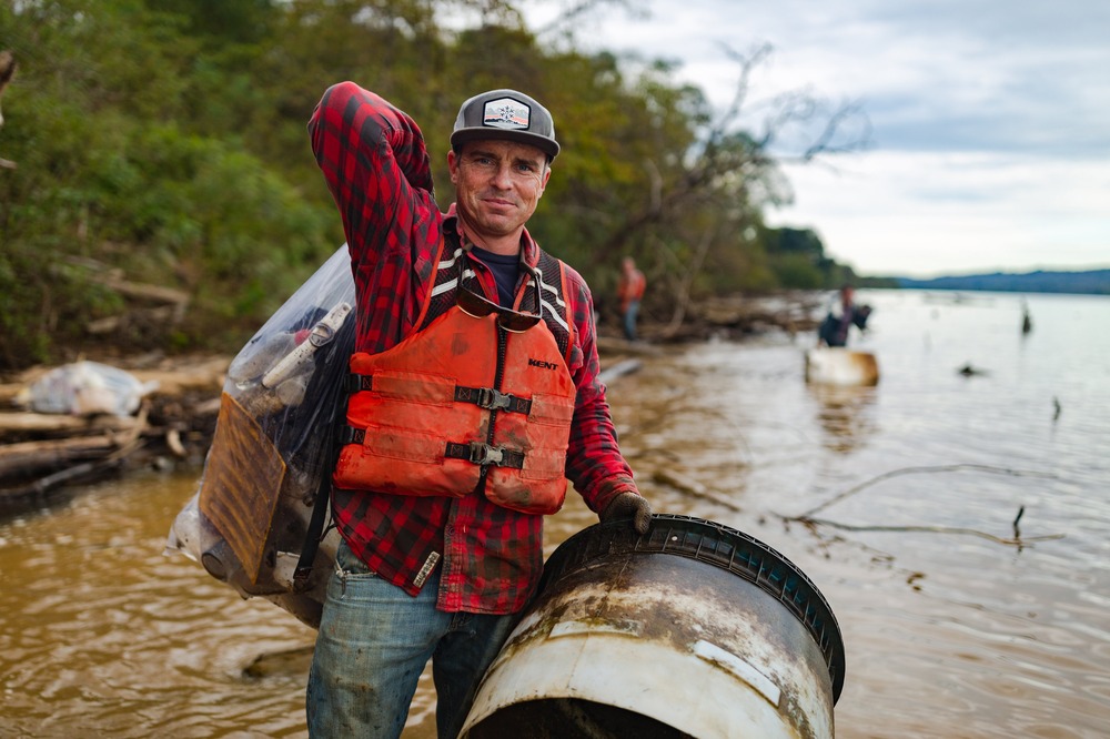 Pregracke stands by river holding debris item.