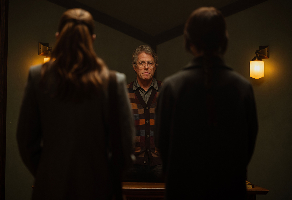 "Heretic" follows two Mormon missionaries, Sister Barnes (Sophie Thatcher) and Sister Paxton (Chloe East) as they visit the home of Mr. Reed (Hugh Grant), who begins questioning the religious beliefs of the women before subjecting them to a claustrophobic roster of horrors that test their beliefs. (A24 Press)