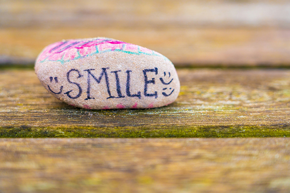 A rock with the word smile on it (Unsplash/Nick Fewings)