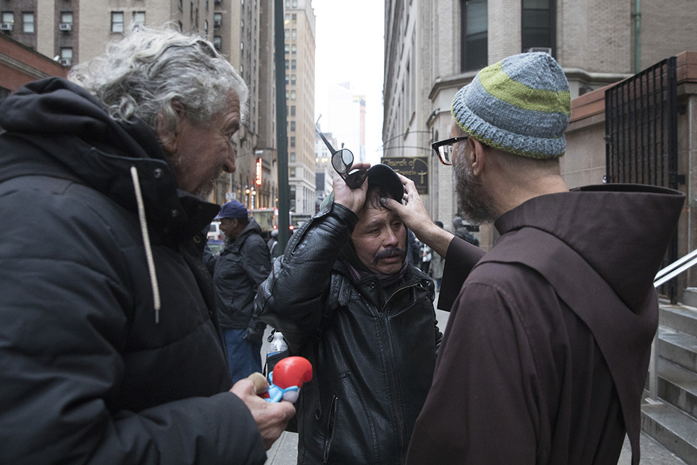 Franciscan Fr. Paul Lostritto marks a cross on the forehead of a homeless man on Ash Wednesday Feb. 14, 2018, at St. Francis Breadline in New York City. (CNS/Octavio Duran)