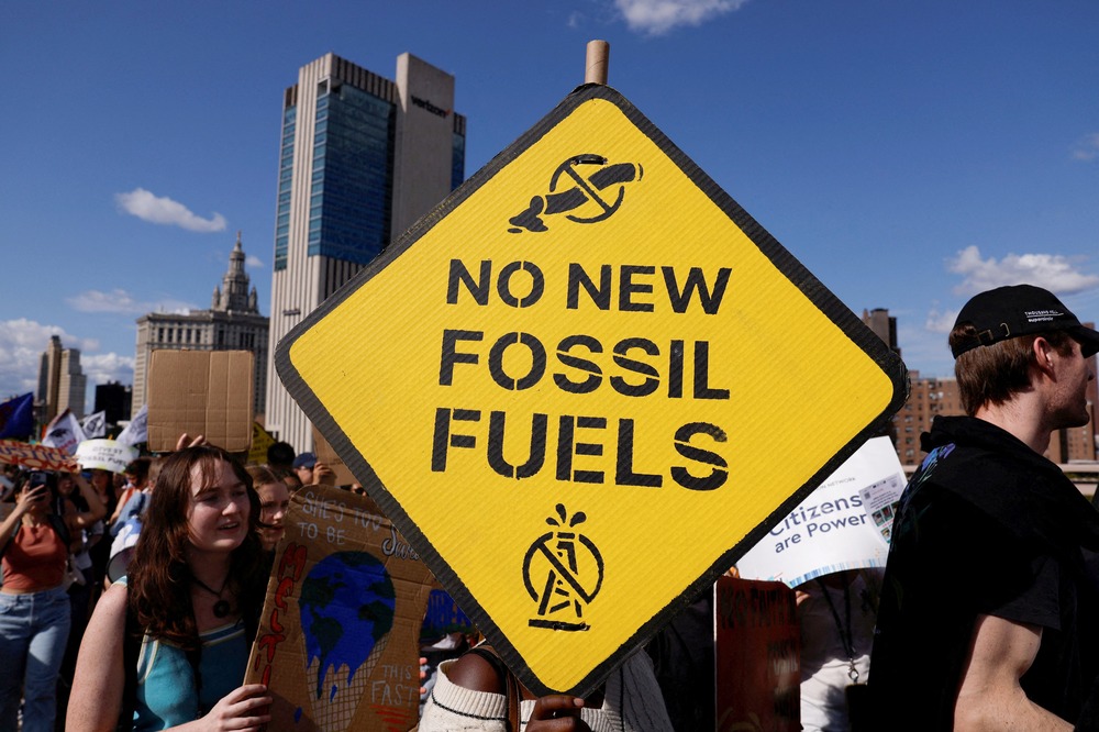 Sign reading "no new fossil fuels" and protestors.