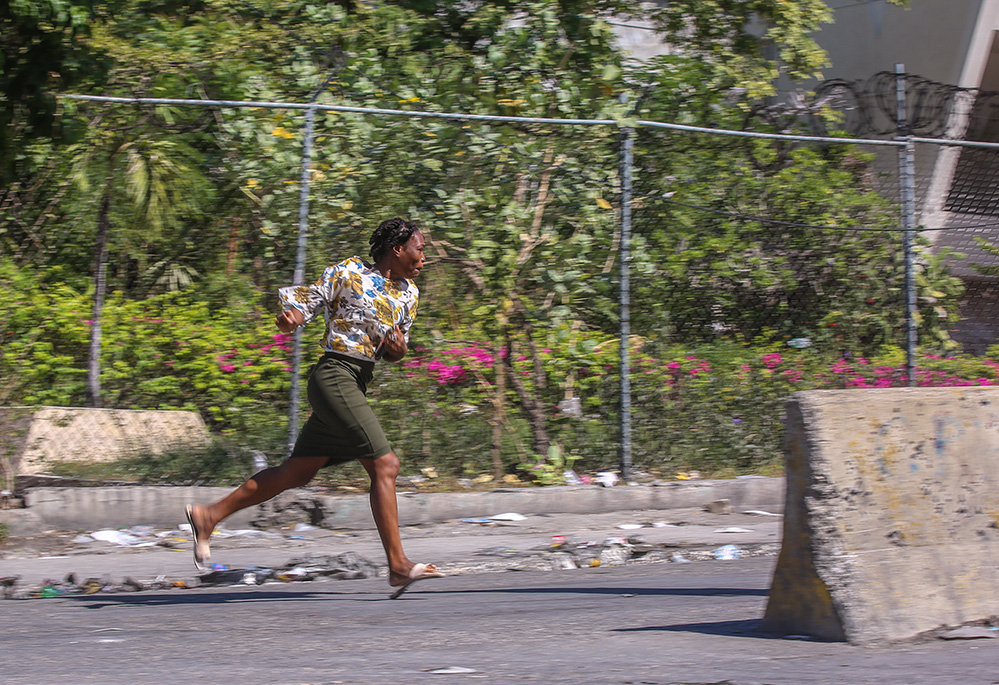 A woman runs to take cover from gunfire during clashes between police and gangs in the Delmas neighborhood of Port-au-Prince, Haiti, Dec. 2, 2024. (AP/Odelyn Joseph)