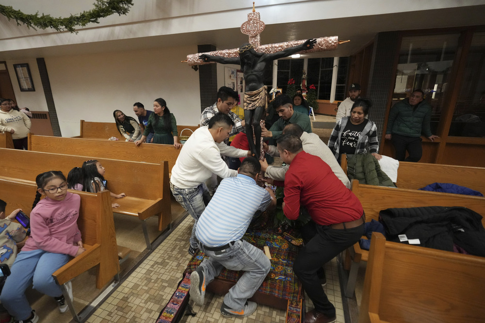 People in church surround large crucifix arranging it into place.