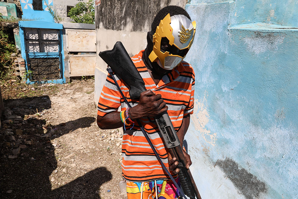 A masked, armed gang member poses for a photo at the National Cemetery during the Fete Gede festival celebrating Day of the Dead in Port-au-Prince, Haiti, Nov. 1, 2024. (AP/Odelyn Joseph)