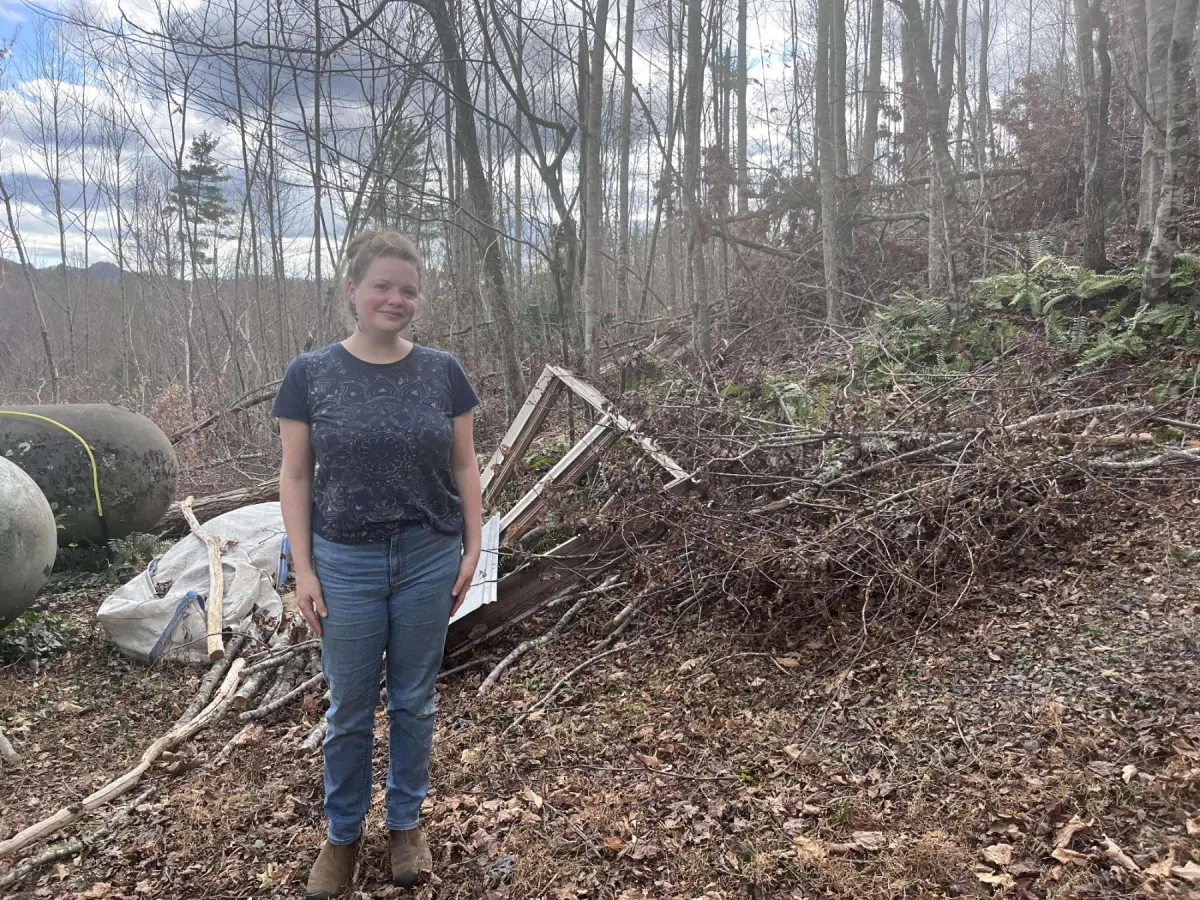 Sarah Ogletree stands in front of downed trees by her house in Bakersville, North Carolina.