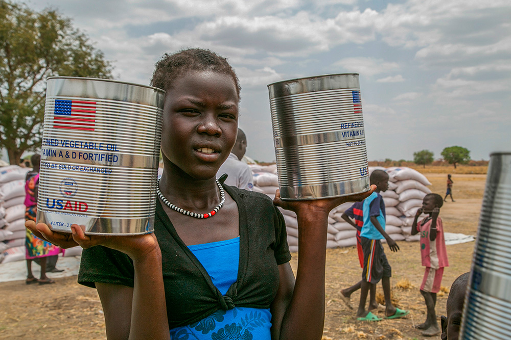 A woman holds cans of vegetable oil provided by the U.S. Agency for International Development in Pajut, South Sudan in 2017. (CNS/Catholic Relief Services/Nancy McNally)