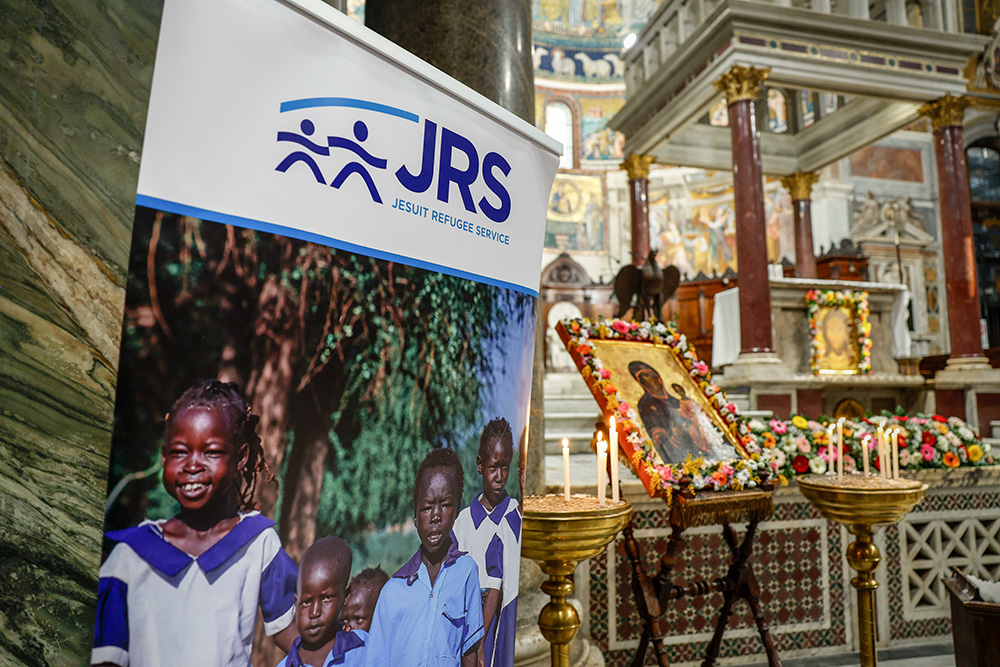 A sign from Jesuit Refugee Service is displayed during an ecumenical prayer vigil in Rome's Basilica of Santa Maria in Trastevere Feb. 6, 2024, as part of a week of raising awareness about human trafficking. (CNS/Lola Gomez)