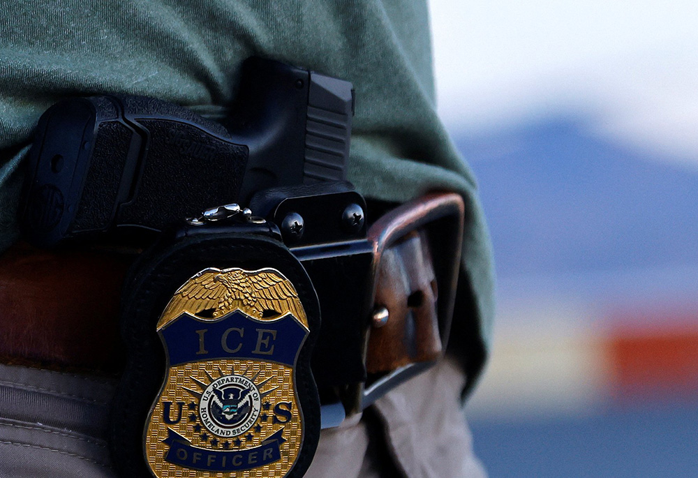 The badge and gun of a U.S. Immigration and Customs Enforcement agent is seen during an operation with migrants being transferred to a plane to be expelled under U.S. Title 42 from the United States to their home country by ICE and Border Patrol agents, at the airport in El Paso, Texas, on May 10, 2023. (OSV News/Reuters/Jose Luis Gonzalez)