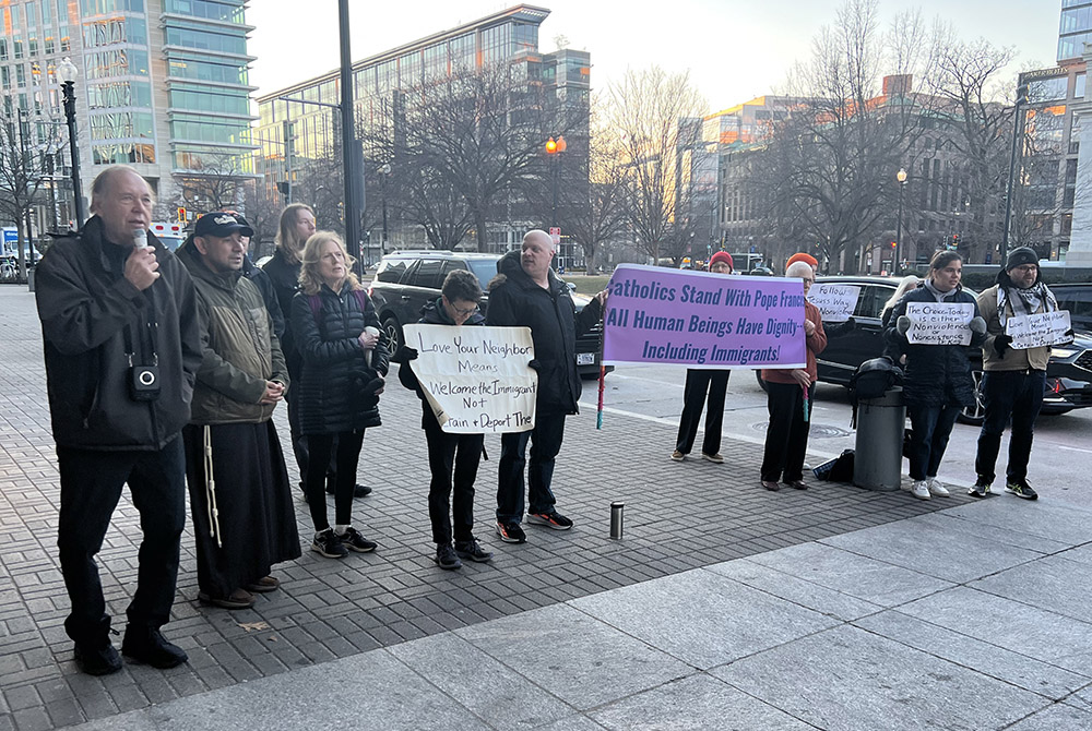 Protesters opposing the Trump administration's immigration policies hold signs Feb. 28 in front of the Walter E. Washington Convention Center in downtown Washington, D.C., where Vice President JD Vance addressed the National Catholic Prayer Breakfast. (NCR photo/Allison Prang)