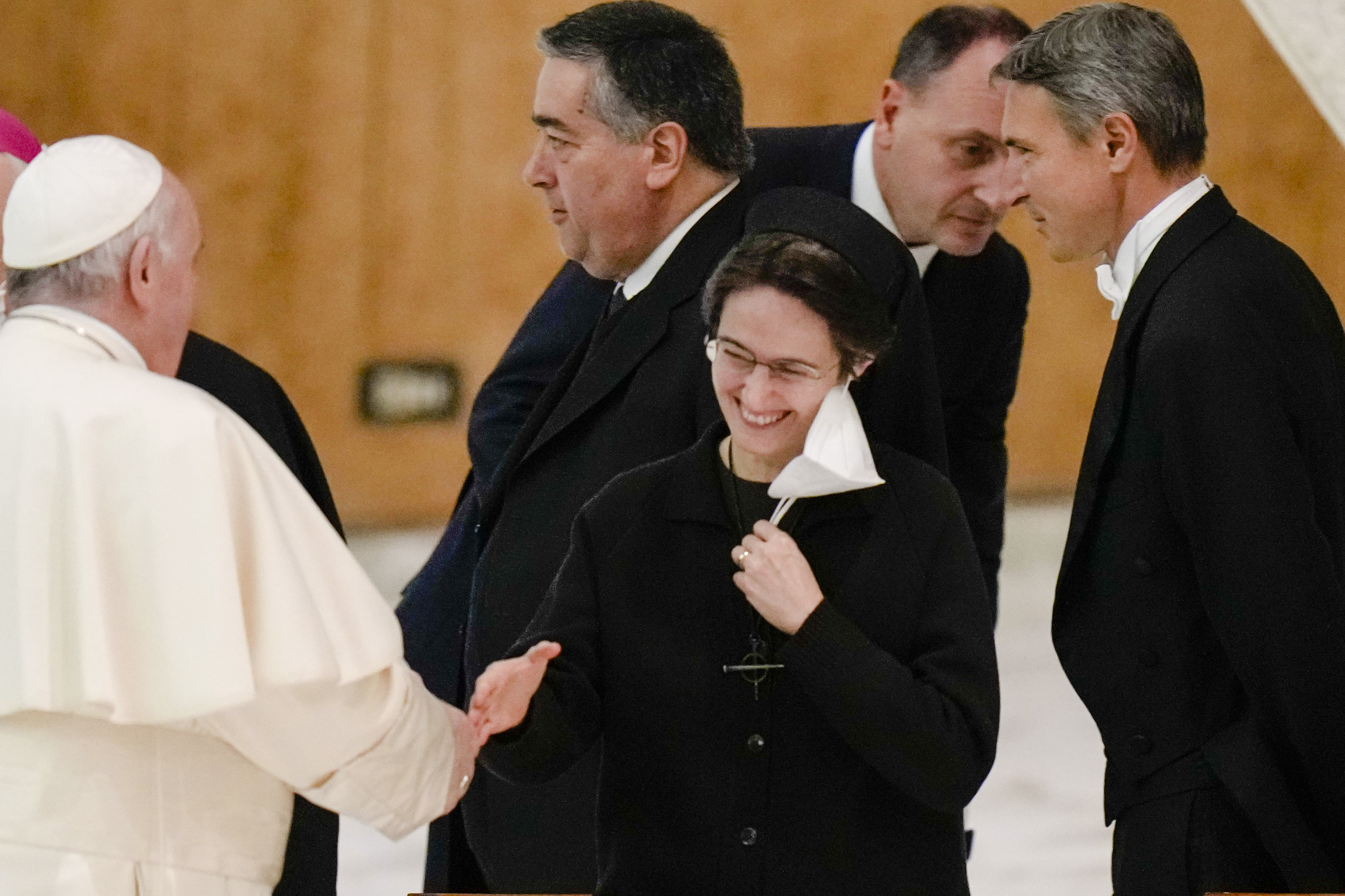 Sr. Petrini smiles at the Pope who is shown from behind shaking her hand.