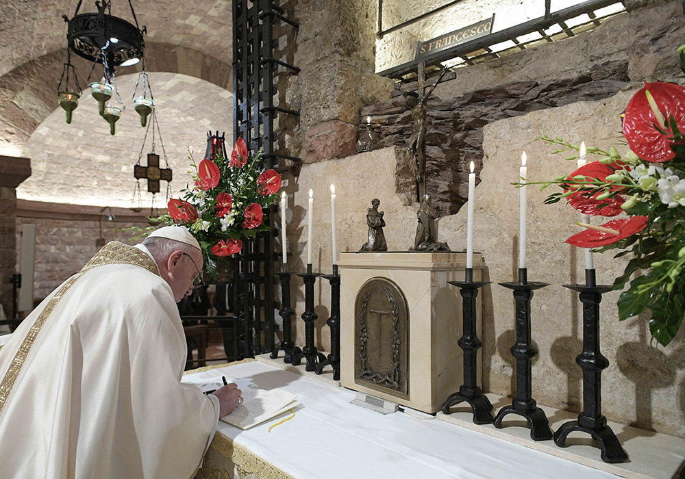 Pope Francis signs his then-new encyclical, "Fratelli Tutti, on Fraternity and Social Friendship" after celebrating Mass at the Basilica of St. Francis in Assisi, Italy, on Oct. 3, 2020. (CNS/Vatican Media)