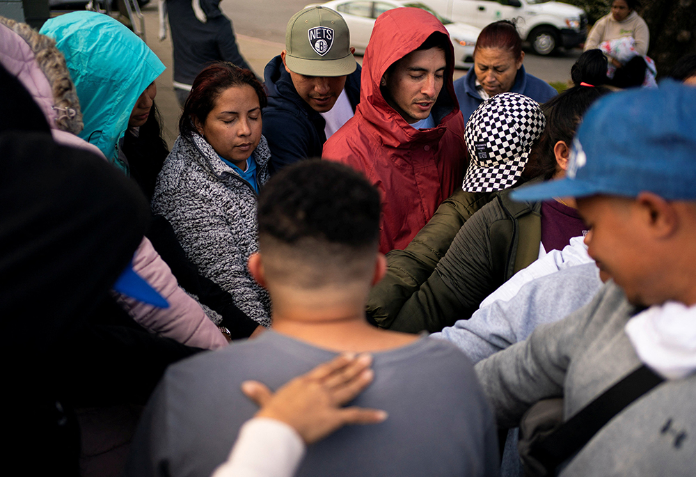 People pray together as a group of mostly Venezuelan migrants camp on the tennis courts of a community center after losing access to another shelter, April 3, 2024, in Seattle. A group of U.S. bishops, including two cardinals, will lead a nine-day Lenten prayer service for migrants and refugees. (OSV News/Reuters/David Ryder)