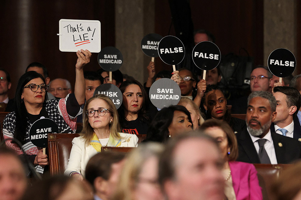 Democrats hold protest signs as U.S. President Donald Trump addresses a joint session of Congress at the U.S. Capitol in Washington March 4, 2025. (OSV News/Reuters/Win McNamee)