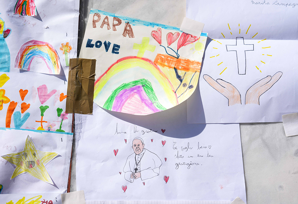 Drawings for Pope Francis are placed at the base of a statue of St. John Paul II outside Rome’s Gemelli Hospital March 6, where the pope has been hospitalized since Feb. 14, receiving treatment for double pneumonia. (CNS/Lola Gomez)