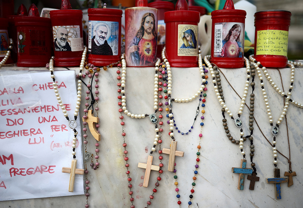 Rosaries hang from the base of the statue of St. John Paul II outside Rome's Gemelli Hospital March 10, where Pope Francis was admitted for double pneumonia Feb. 14. (OSV News/Reuters/Guglielmo Mangiapane)