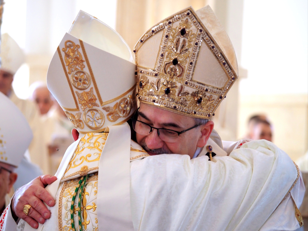 Cardinal Pierbattista Pizzaballa, facing the camera, embraces Iyad Twal, the newly ordained auxiliary bishop of the Latin Patriarchate of Jerusalem who's facing away from the camera. (Francesca Maria Lorenzini)