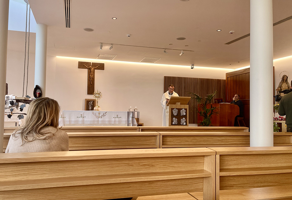 Fr. Nunzio Currao, the leading spiritual assistant to the Gemelli medical and hospital staff of more than 6,000 employees, places his phone on the microphone and plays the audio clip where Pope Francis thanks Catholics worldwide for their prayers for him. (NCR photo/Camillo Barone)