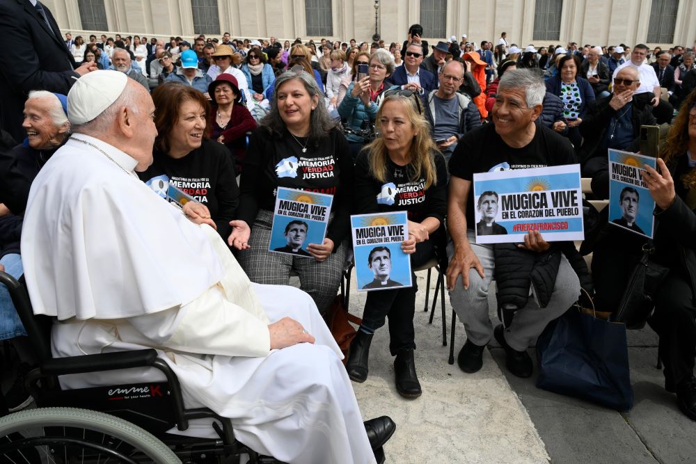 Pope Francis greets a group of Argentine visitors holding images of Fr. Carlos Mugica, an Argentine priest and activist. 