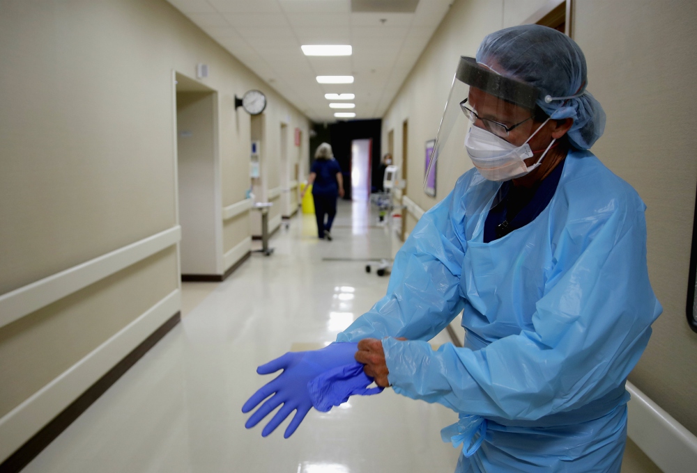 Registered nurse Kevin Hoover puts on protective gear as he prepares to check on a COVID-19 patient May 20 at the rural 24-bed Kearny County Hospital in Lakin, Kansas. The county has seen a spike in cases due to clusters in nearby meatpacking plants. (AP)