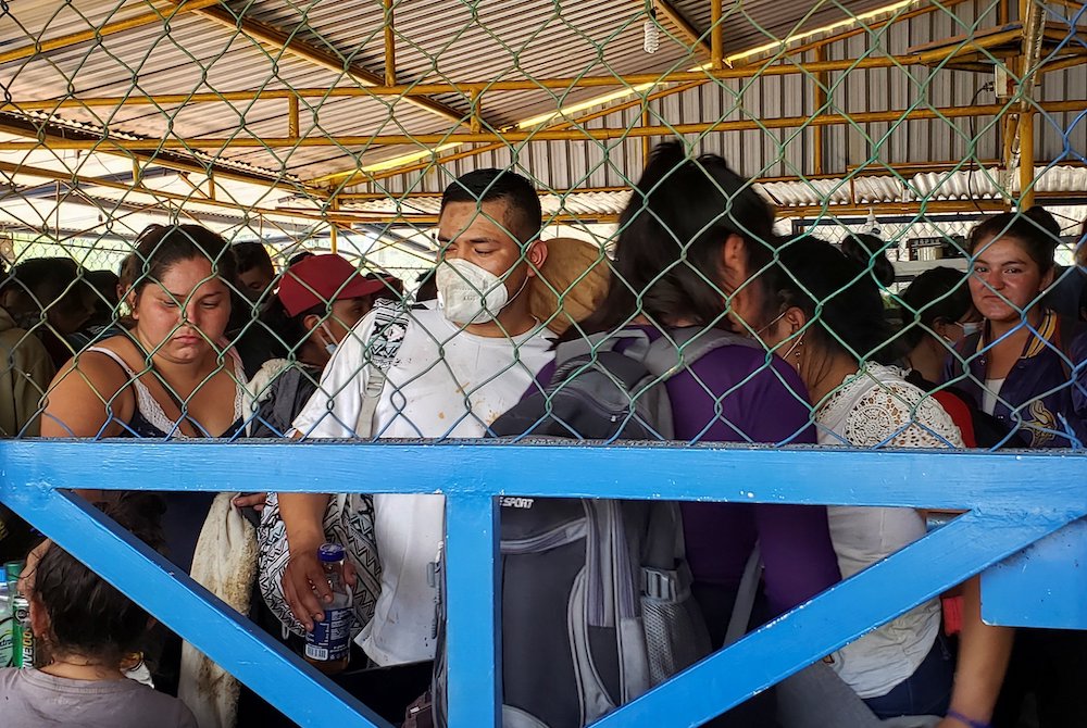 Migrants from Central America seeking asylum in the U.S. are pictured through a fence in Nuevo Teapa, Mexico, Jan. 21, 2021. (CNS/Reuters/Tamara Corro)