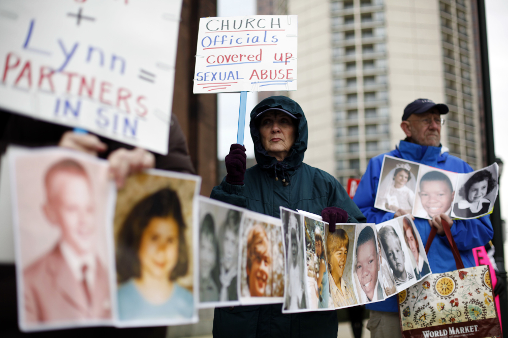 Catherine Coleman Murphy, center, and Jack Wintermyer, right, protest along with others outside Cathedral Basilica of Sts. Peter and Paul before an Ash Wednesday Mass in Philadelphia on March 9, 2011. (AP/Matt Rourke)