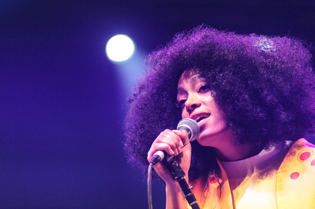 Solange holding a microphone and singing