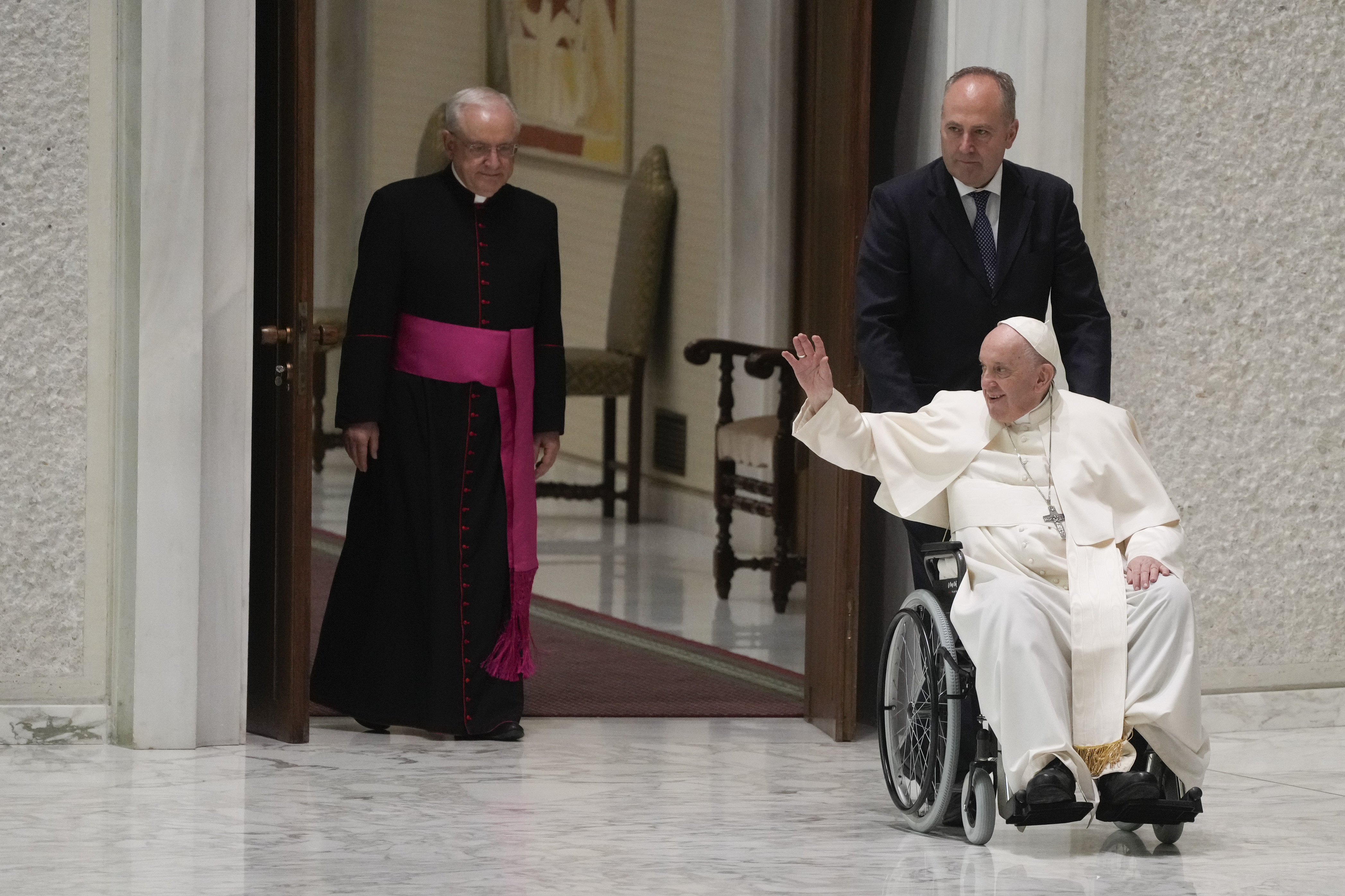 Pope Francis arrives in a wheel chair in the Paul VI hall to attend an audience with pilgrims from central Italy at the Vatican, Saturday, May 14, 2022. (AP Photo/Gregorio Borgia)