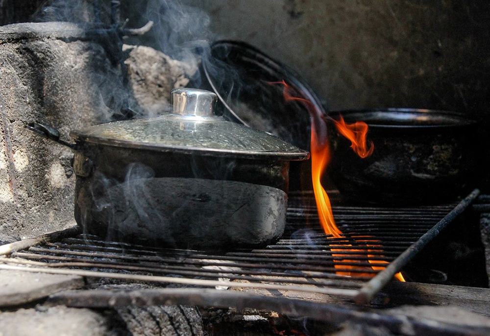 Neilma da Cruz Silva uses scrap wood for cooking fuel in April 2020, in a low-income neighborhood in Rio de Janeiro. (Bruno Itan)