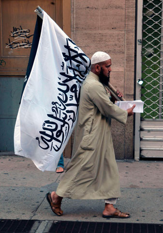 On Sept. 11, 2010, a Muslim man holds out literature to people at protests over the construction of a Muslim community center in Manhattan, N.Y. (Newscom/SIPA/Terrence Jennings)