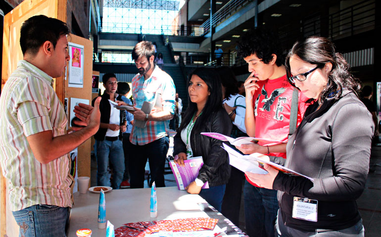 Nelson Pineda, a volunteer from Aspidh Arcoiris Trans de El Salvador, speaks with conference attendees in front of a memorial to trans women who have been murdered in El Salvador in the past decade.  Aspidh Arcoiris is a Salvadoran non-profit organization that works primarily with transgender, transsexual and transvestite individuals in the areas of human rights and HIV prevention. (Courtesy of ALDES El Salvador)