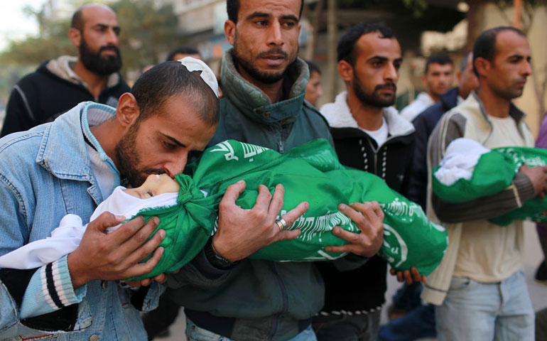 A Palestinian man kisses the body of one of his children during a funeral in the northern Gaza Strip Nov. 18. An Israeli missile ripped through a two-story home in a residential area of Gaza City, killing at least 11 civilians. (CNS/Reuters/Mohammed Salem)