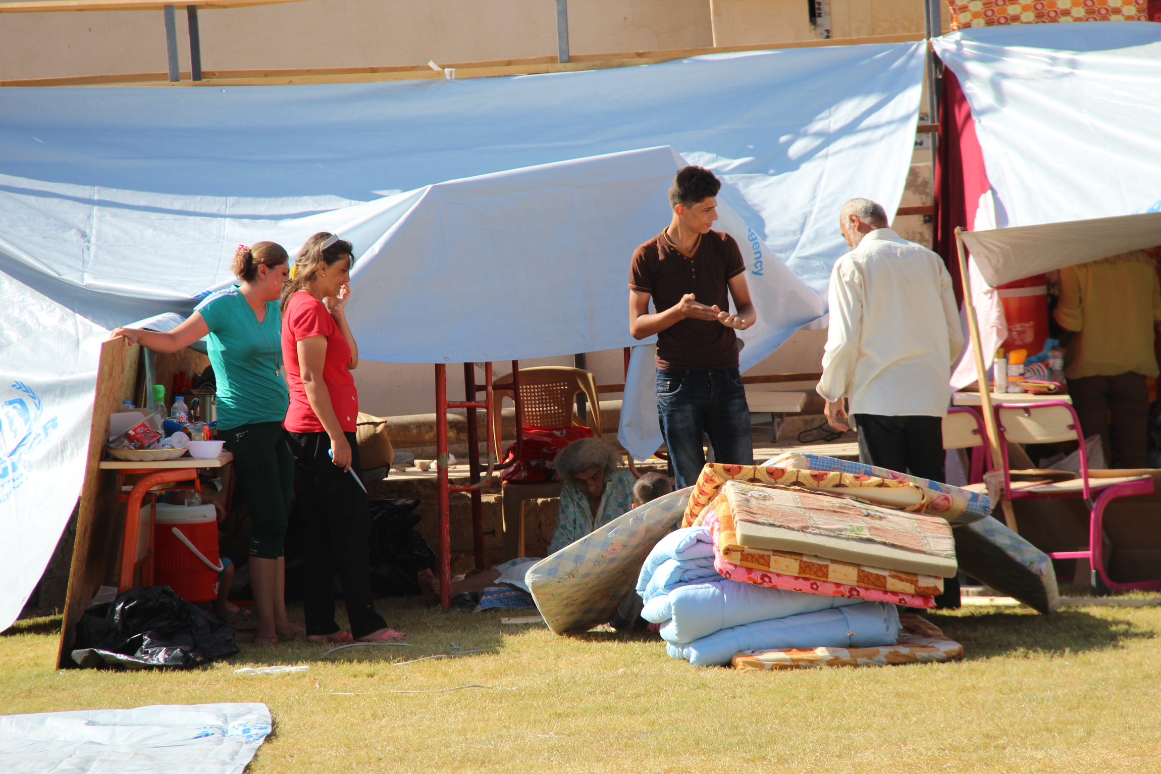 People displaced by violence stand outside their tent at St. Joseph Chaldean Catholic Church in Ankawa, Iraq, Aug. 14. (CNS/courtesy Aid to the Church in Need-USA)