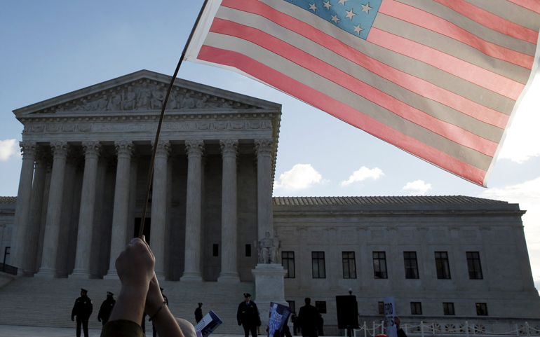 A person holds up the American flag in front of the U.S. Supreme Court in Washington March 2. (CNS/Kevin Lamarque, Reuters)