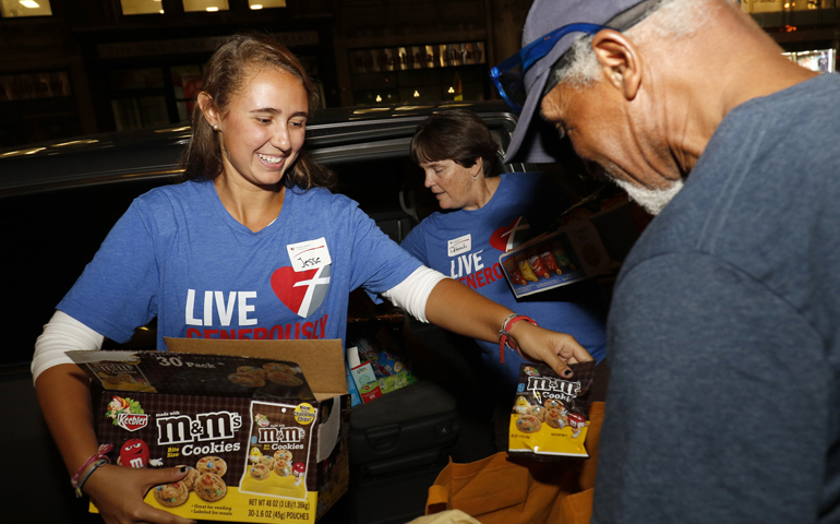 Jesse Damm hands a snack to a homeless man during a late-night visit by the youth group of Good Shepherd Church in Holbrook, N.Y., to New York City Aug. 26. (CNS/Gregory A. Shemitz)