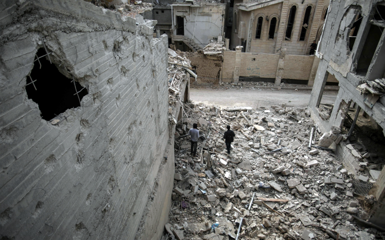 Men walk in rubble Nov. 13 near St. Mary's Catholic Church and St. Elias Orthodox Church after a bombing in Damascus, Syria. Christians in the Middle East face extinction because of genocide, wars and international indifference to their plight, said speakers at a Dec. 5 panel discussion in New York. (CNS photo/Mohammed Badra, EPA)