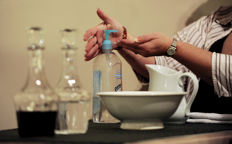 An extraordinary minister of holy Communion uses hand sanitizer kept on the credence table during a 2009 Mass at Our Lady of the Americas Church in Rochester, N.Y. Faith communities in the Rochester Diocese were urging "common sense" measures to avoid spreading the H1N1 and seasonal flu viruses, measures that could be put back into place with this year's flu epidemic. (CNS/Catholic Courier/Mike Crupi)