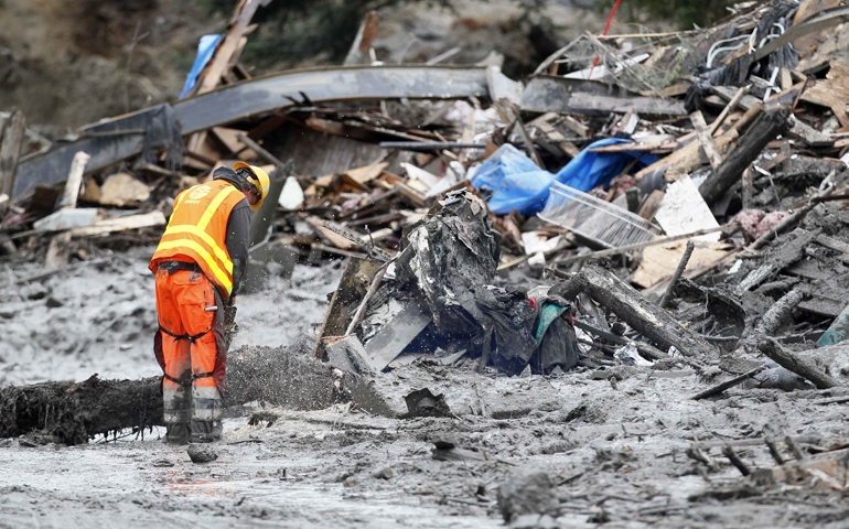 A worker uses a chain saw Wednesday to break up a tree in the mudslide near Oso, Wash., as rescue efforts continued. (CNS/Reuters/Rick Wilking)