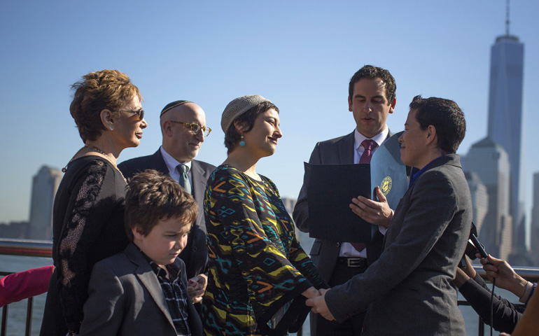 Meredith Greenberg holds hands with her partner, Leora Pearlman, as Mayor Steven Fulop of Jersey City, N.J., presides over their wedding Monday in Jersey City, the same day New Jersey became the 14th U.S. state to legalize same-sex marriage. (CNS/Reuters/Shannon Stapleton)